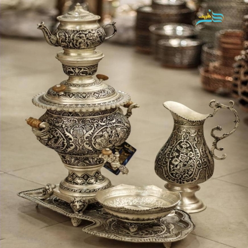 نمای کامل از سماور برنجی با قلمزنی سیاه قلم و آبکاری پتینه نقره، نمایش فرم، ارتفاع ۶۳ سانتی و زیبایی کلی.